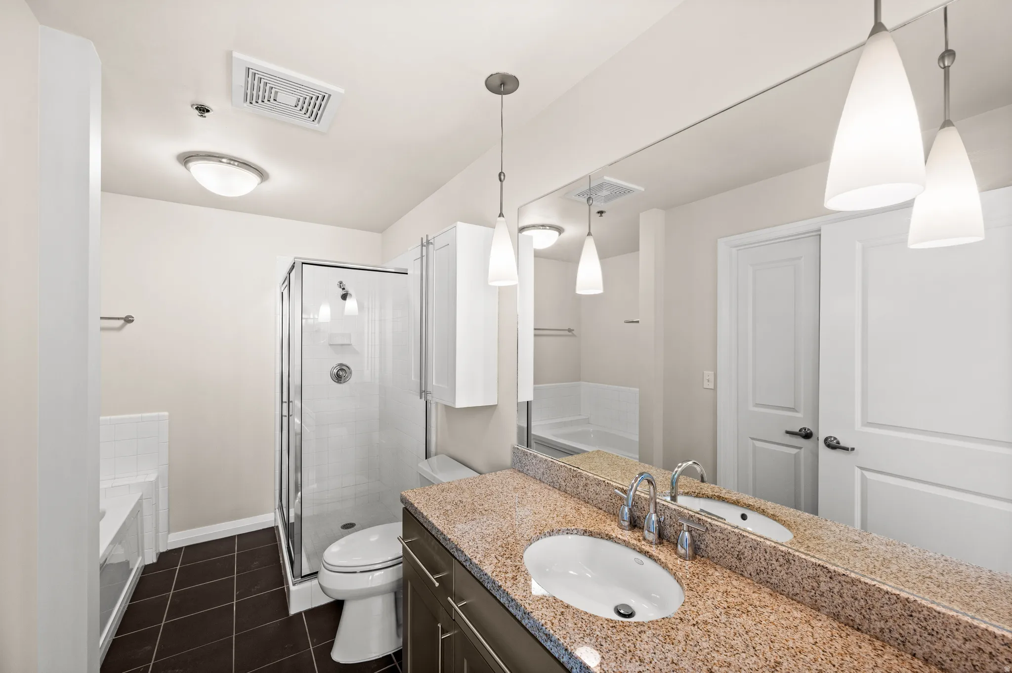 Bathroom featuring a dual-sink vanity with a granite countertop and chrome fixtures