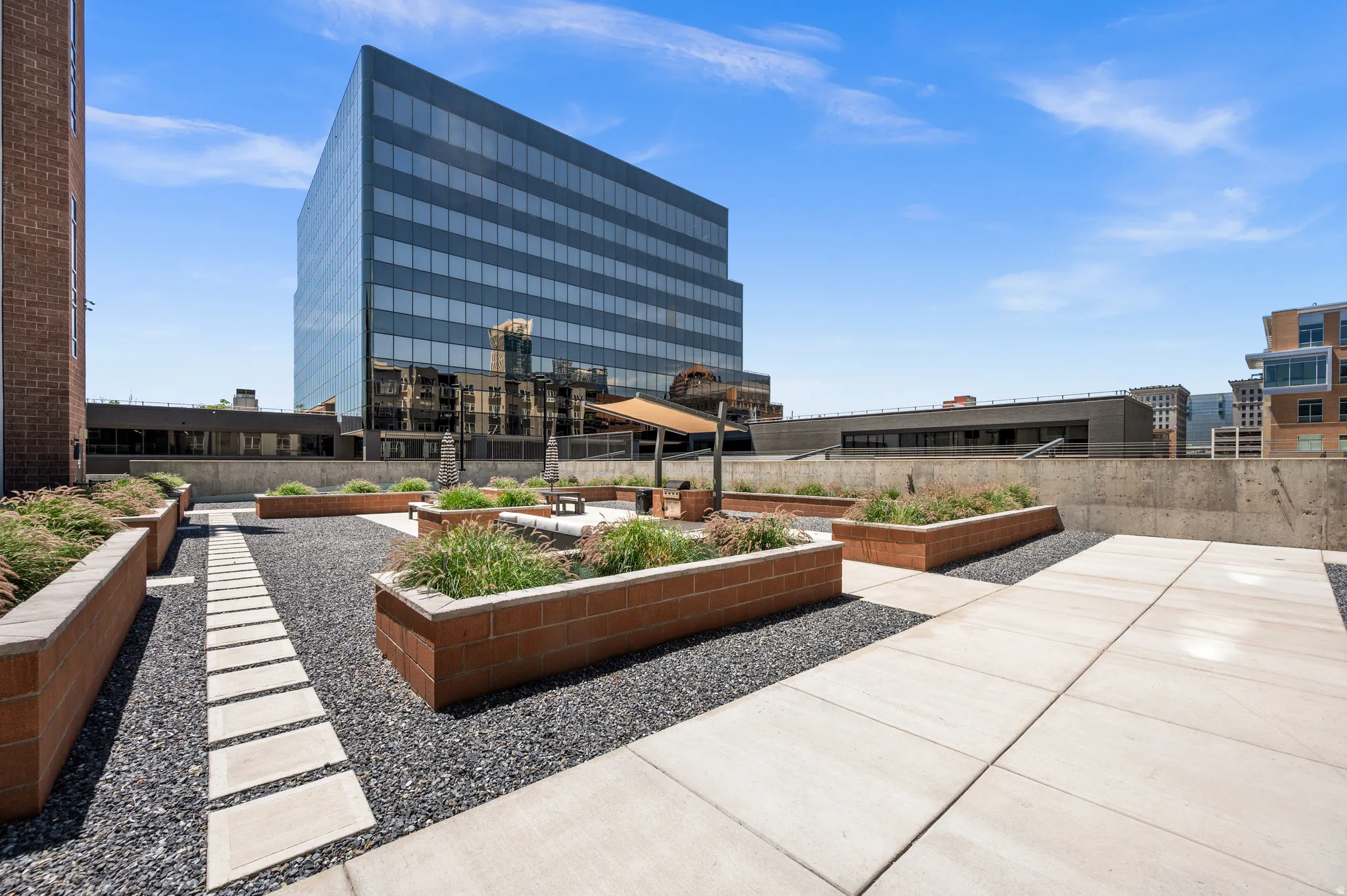Rooftop patio featuring expansive hardscaping with integrated planters, concrete paver pathways, and a gravel ground cover