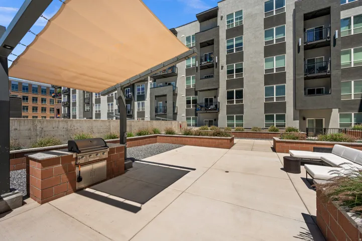 Spacious outdoor patio featuring a built-in grill station with brick accents and a sun shade structure