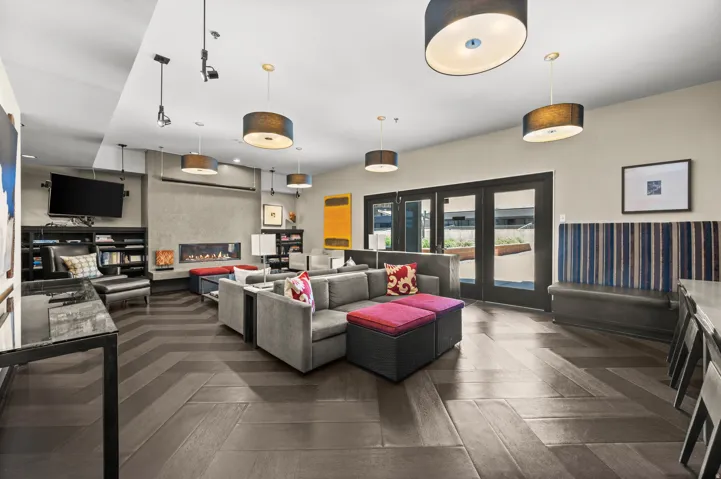 Spacious gathering room featuring wood-finish flooring with a herringbone pattern, a built-in linear fireplace, and multiple drum pendant lights