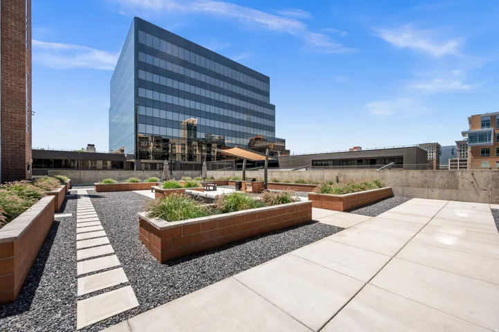 Rooftop patio featuring expansive hardscaping with integrated planters, concrete paver pathways, and a gravel ground cover