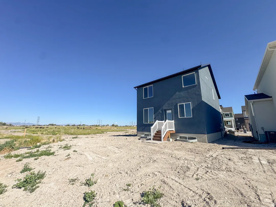 Rear exterior featuring blue siding, a white-railed staircase, and multiple windows
