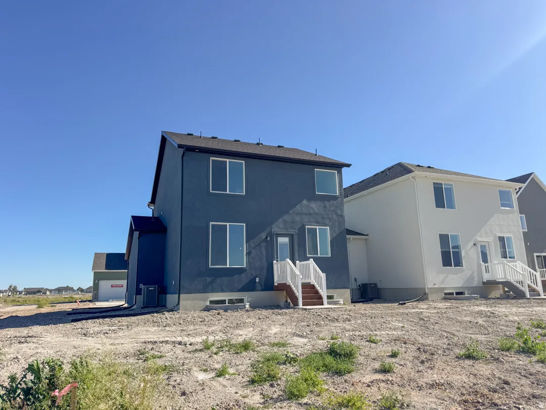 New construction residence featuring a deep blue stucco exterior and a dark shingle roof