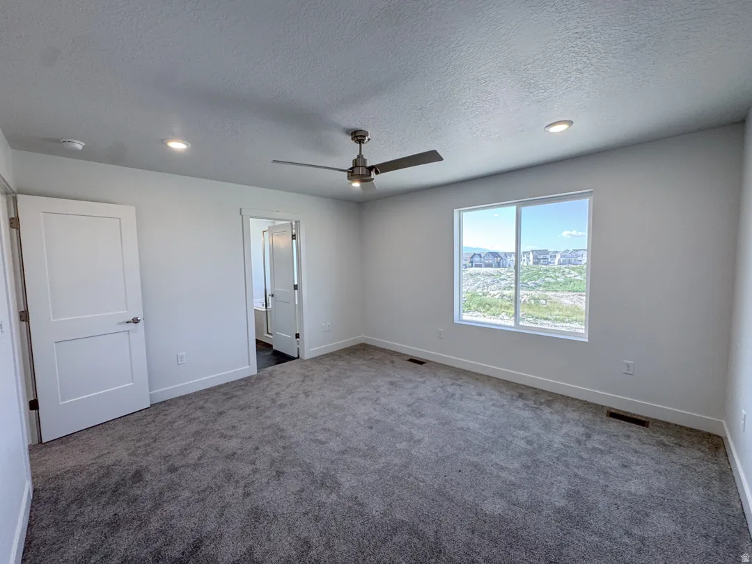Spacious room featuring gray carpet flooring, white walls, and a large window