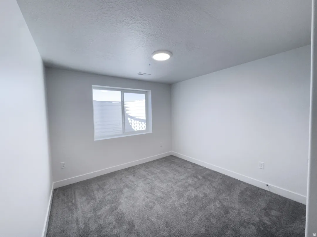 Room featuring neutral wall tones, gray carpeting, white baseboards, and a single window with a white frame