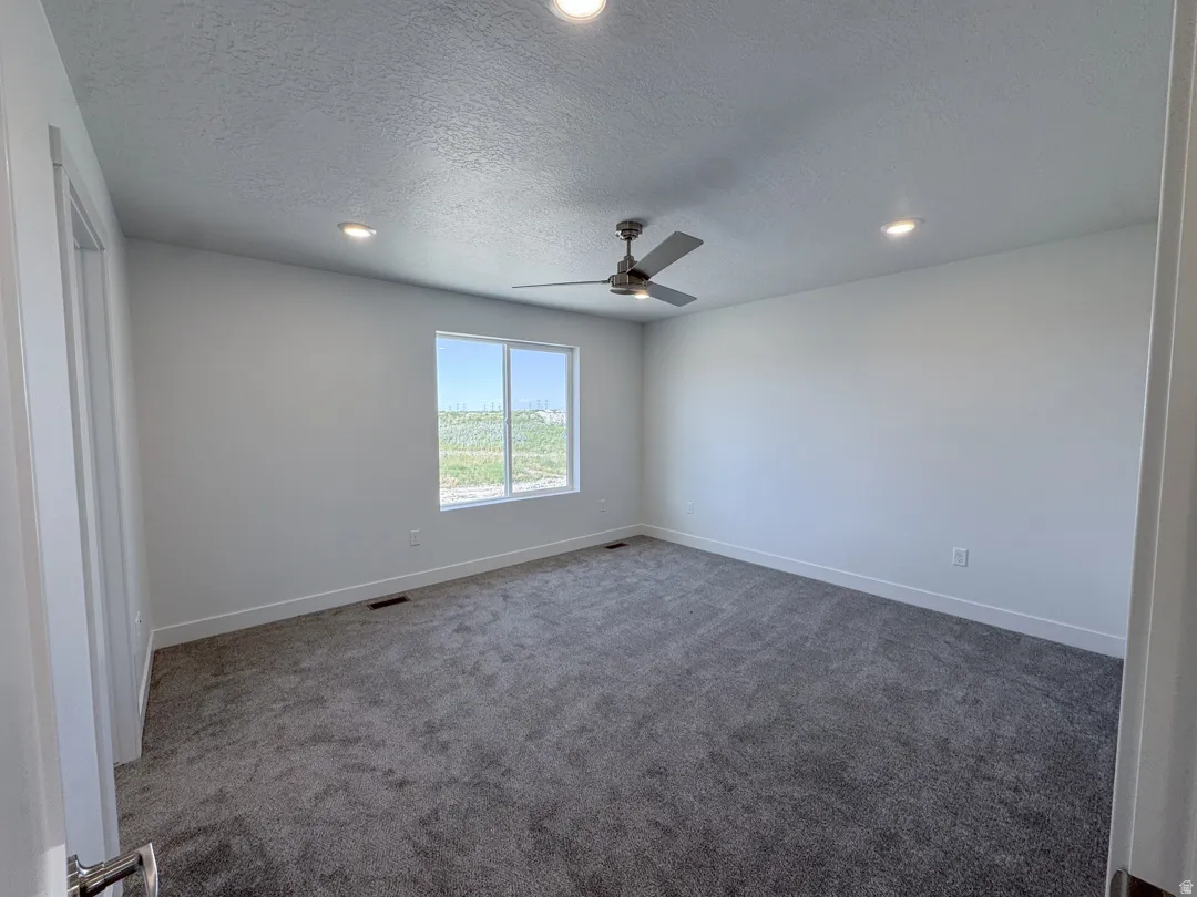 Spacious room featuring neutral paint, gray carpeting, a modern ceiling fan, recessed lighting, and a large window