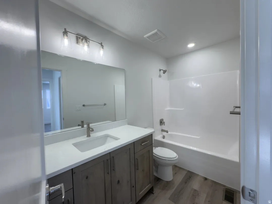 Full bathroom featuring a single vanity with wood-finish cabinetry, a white countertop, and an integrated sink