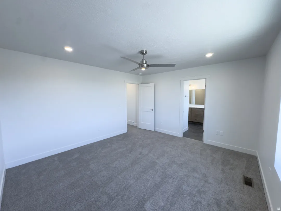 Spacious room featuring gray carpet flooring, recessed lighting, and a ceiling fan