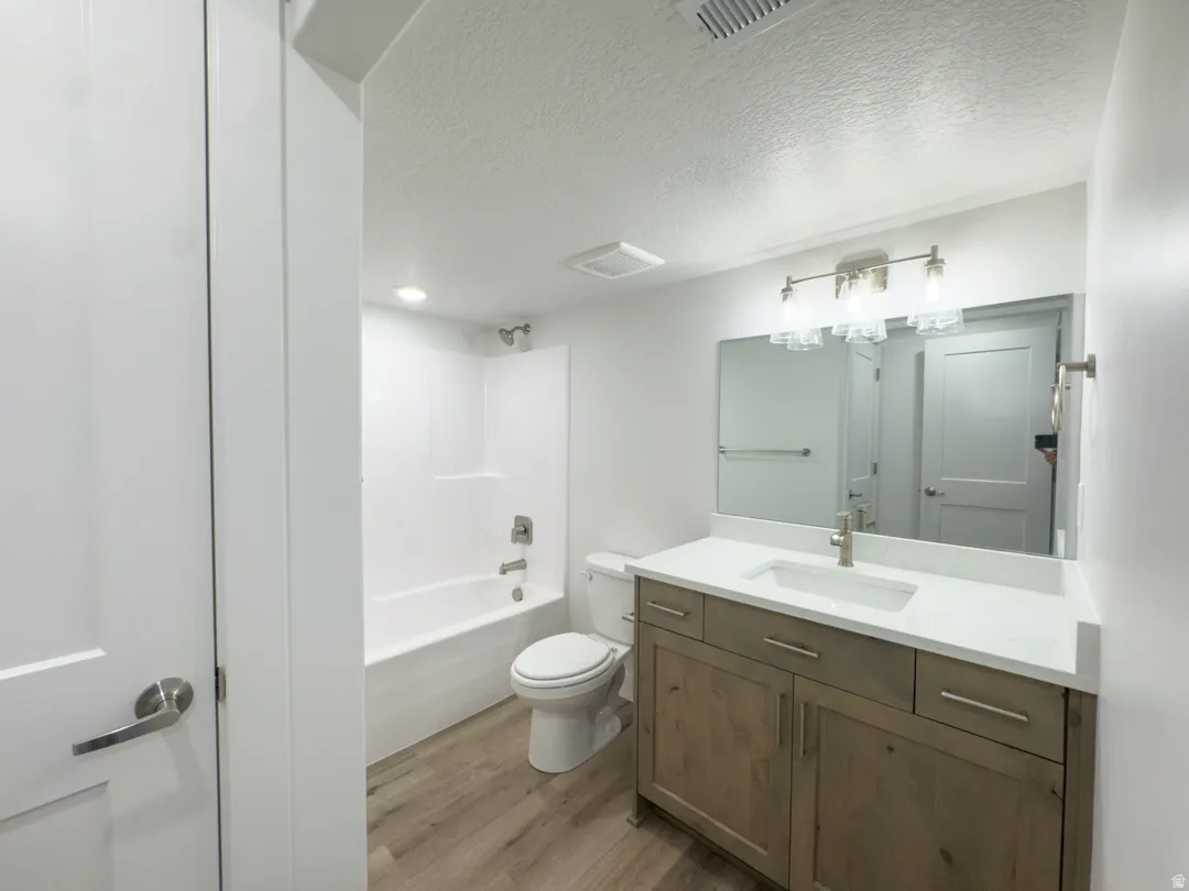 Bathroom featuring a wood-finish vanity with a light countertop, integrated sink, and brushed nickel fixtures