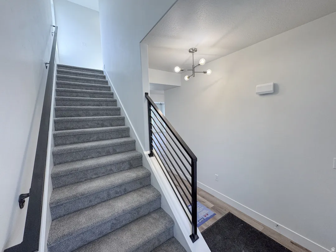 Carpeted staircase with contemporary horizontal metal railings and a coordinating wall-mounted handrail