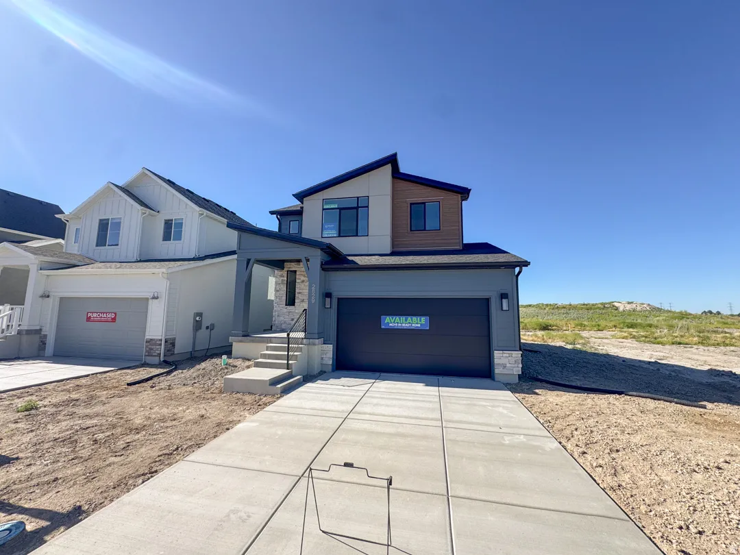Contemporary-style home featuring a dark gray garage door, light gray siding, and stone accents