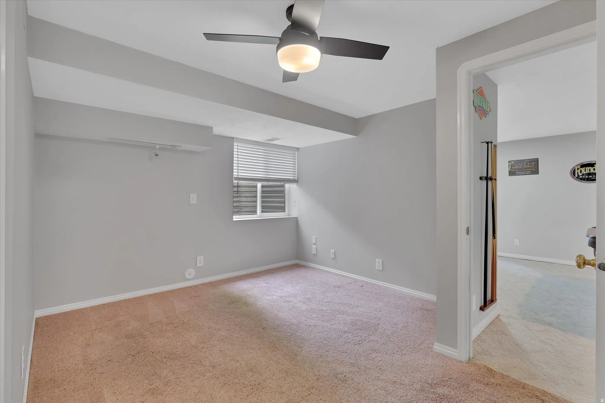 Carpeted room featuring a ceiling fan with integrated lighting, a window with blinds, and light gray painted walls
