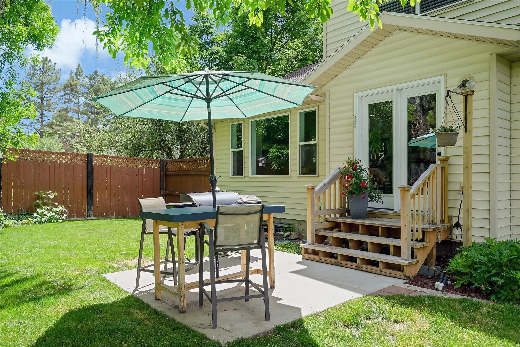 Expansive backyard featuring a manicured lawn, concrete patio, and mature perimeter fencing