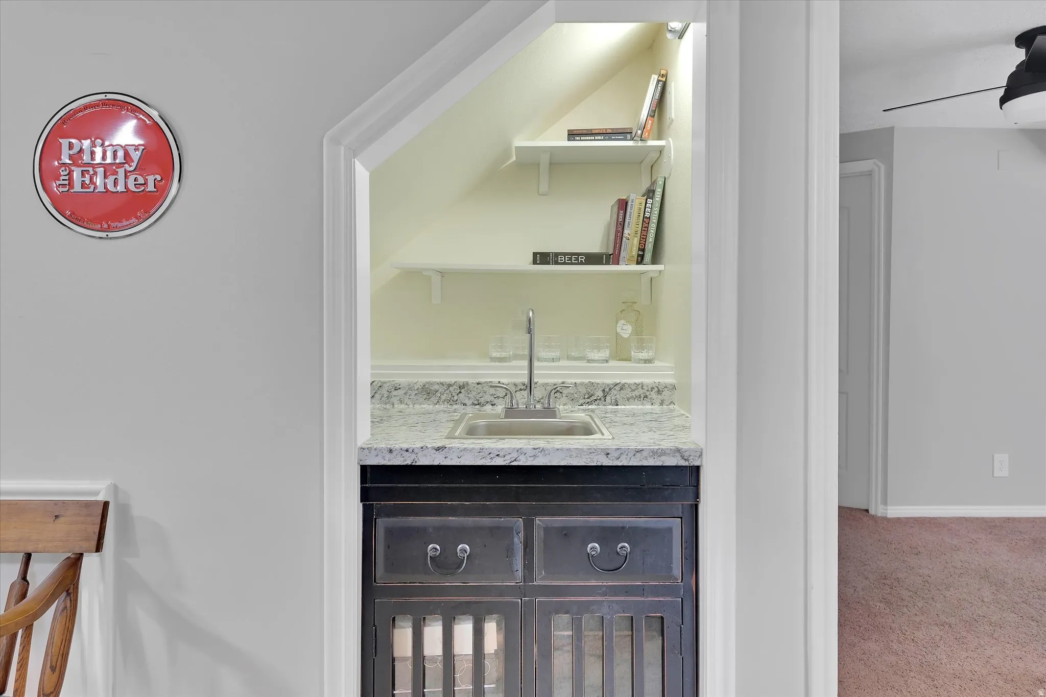 Built-in wet bar featuring a stainless steel sink, speckled countertop, and dark wood-finish cabinetry