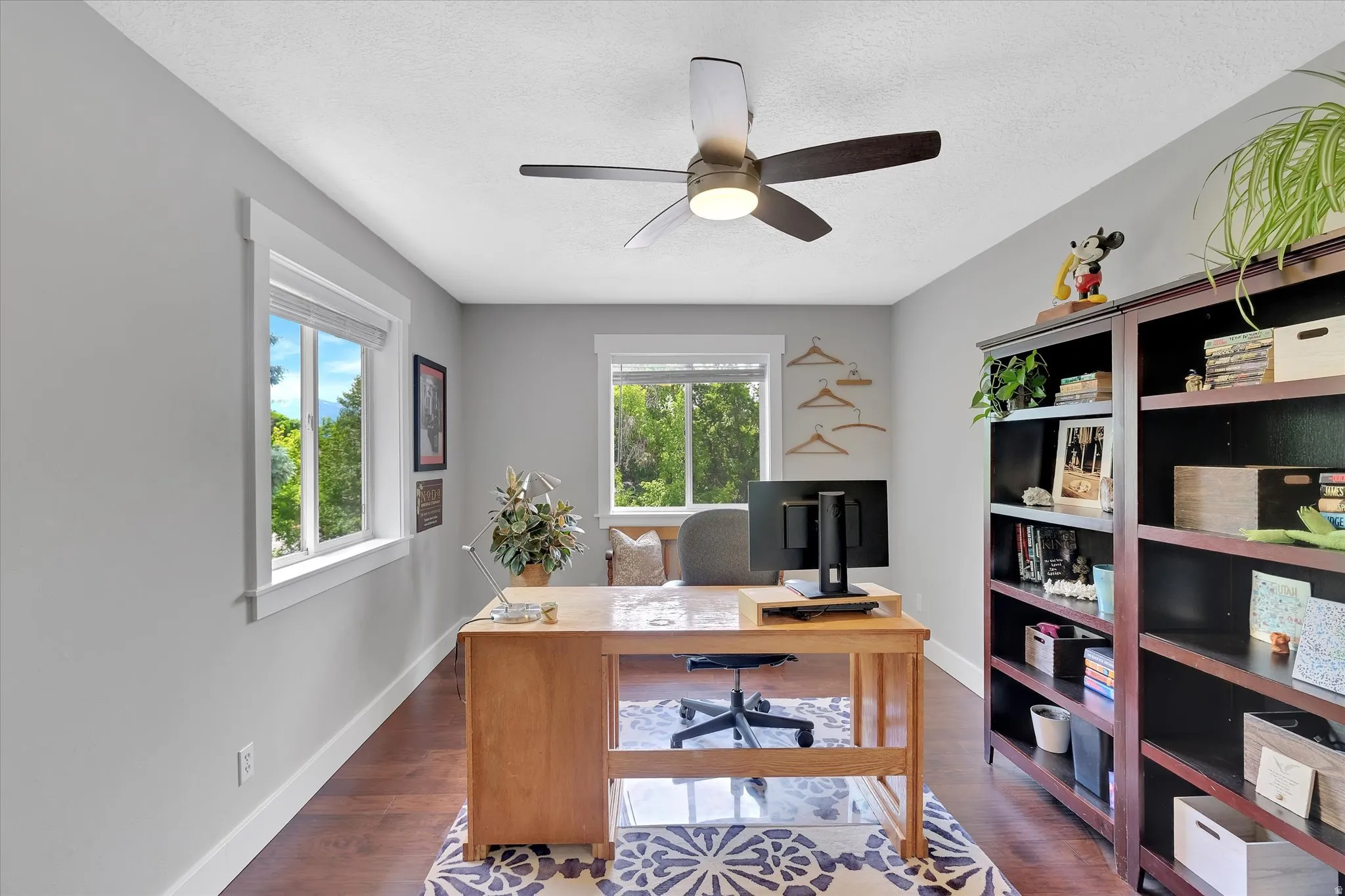 Spacious room featuring wood-finish flooring, light grey painted walls, white trim work, and two windows