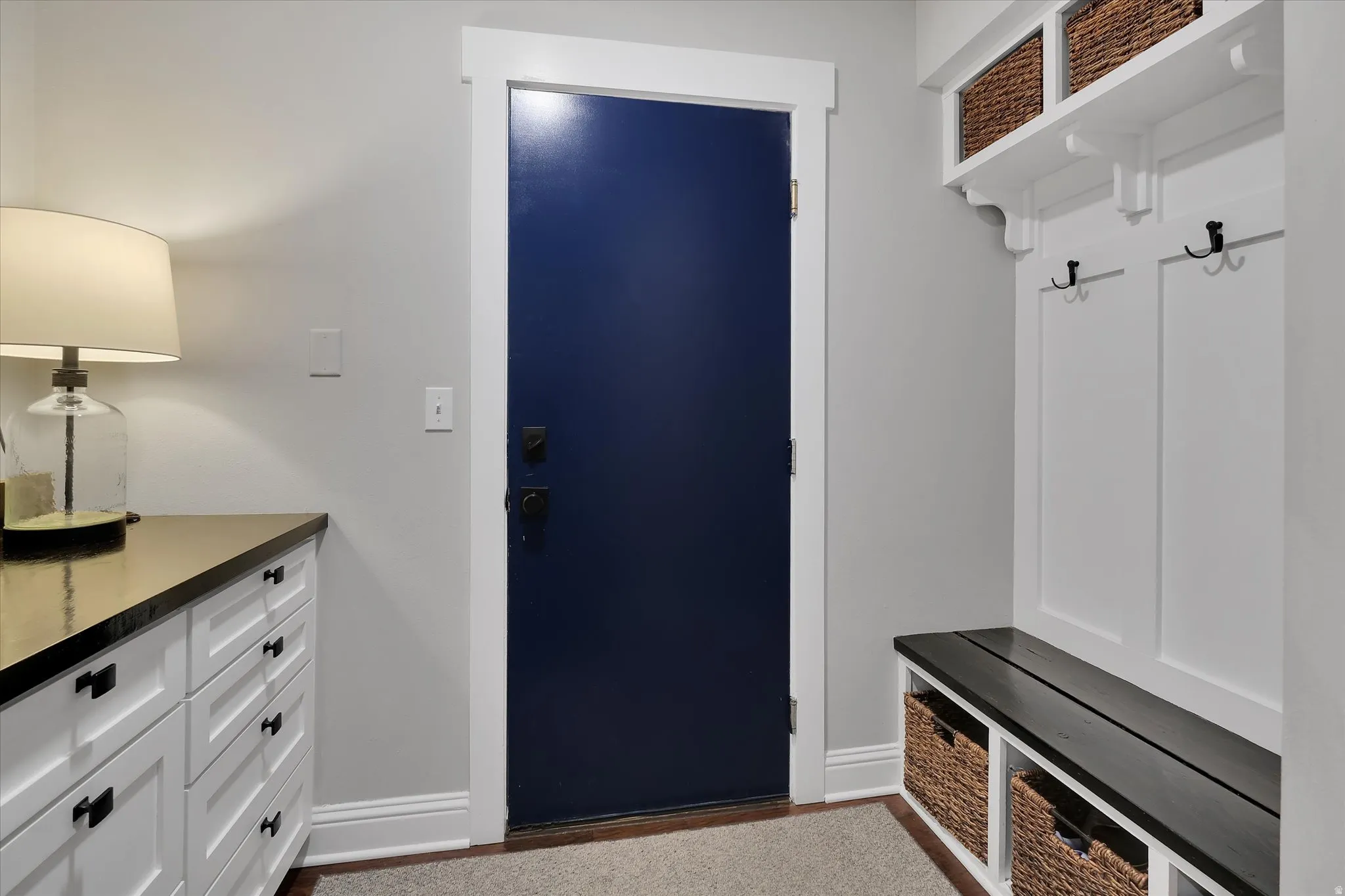 Entryway featuring a navy blue door, white trim, and a built-in mudroom bench with storage