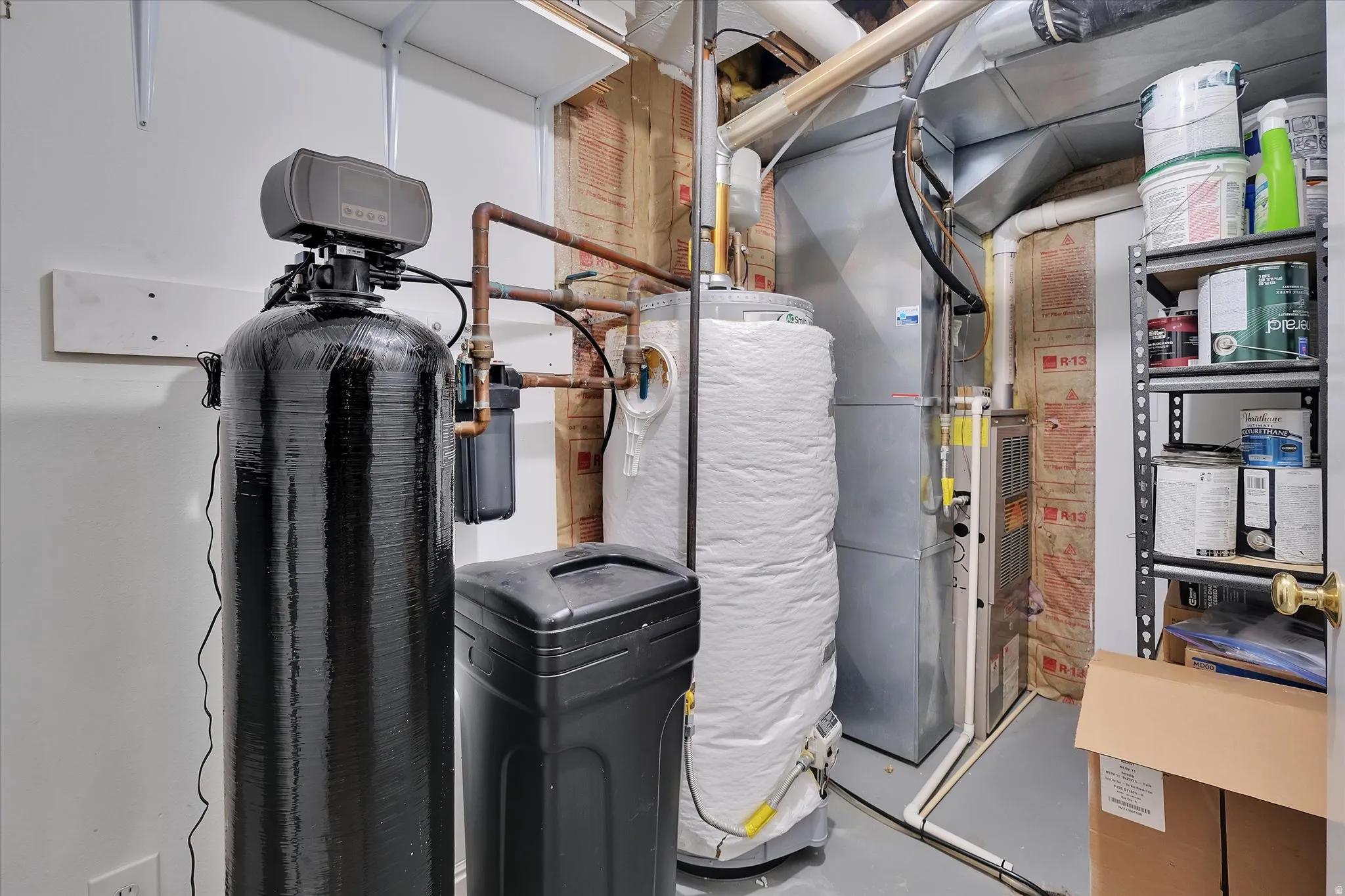 Utility area featuring a water softener system, water heater, and furnace
