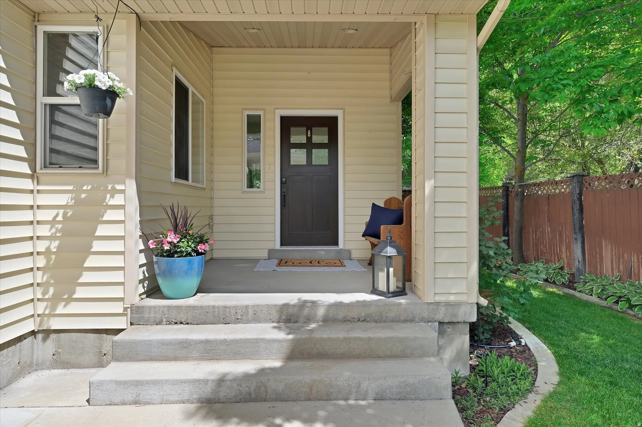 Covered front porch with light-toned siding and a dark entry door