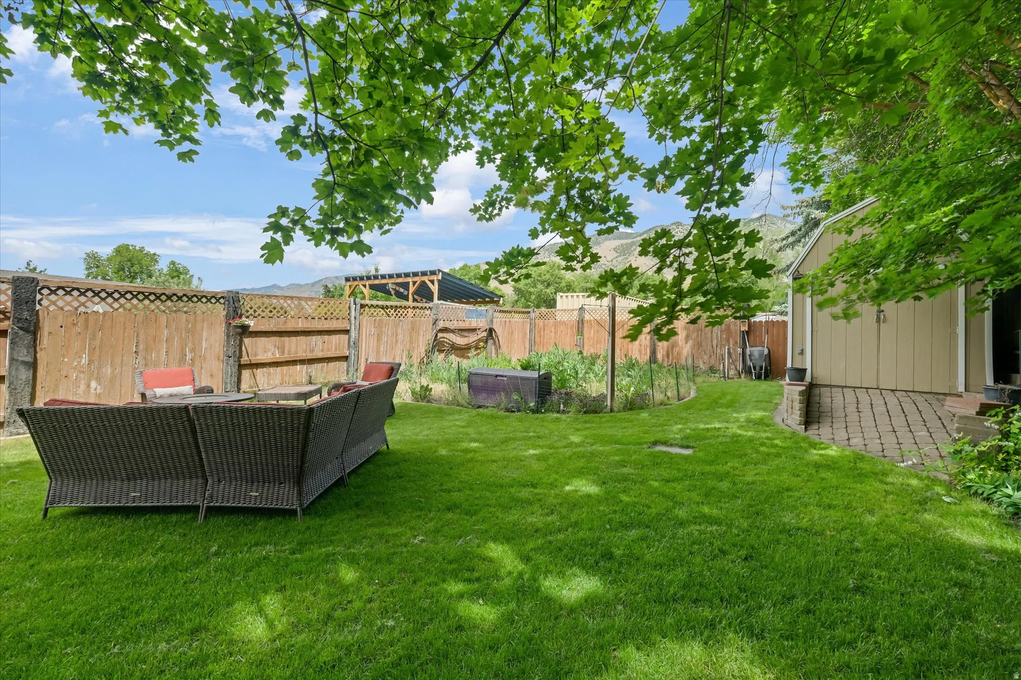 Expansive backyard featuring a lush lawn, solid wood fencing with lattice accents, and mature trees providing natural shade