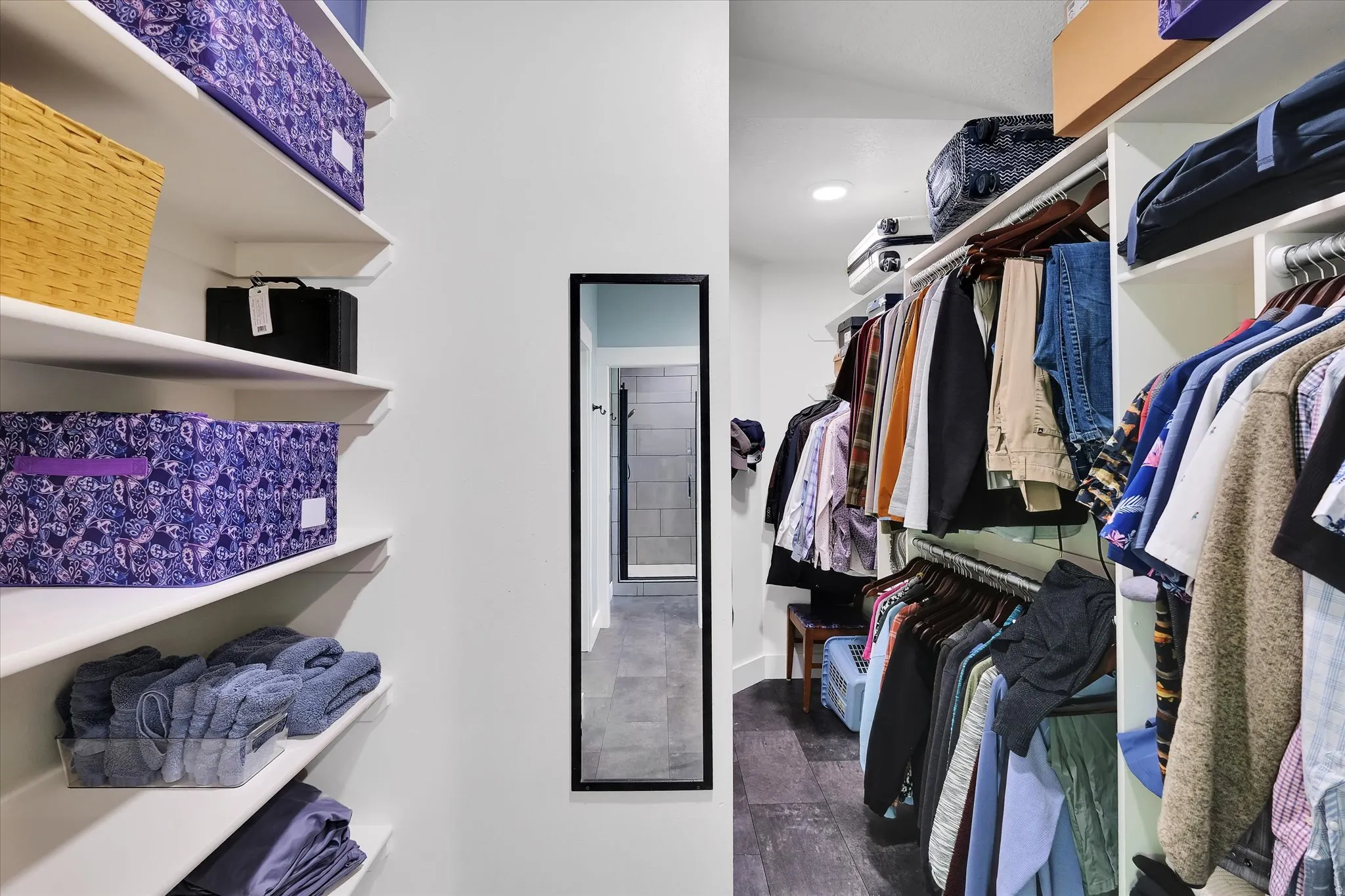 Walk-in closet featuring white built-in shelving, multiple hanging rods, recessed lighting, and dark wood-finish flooring