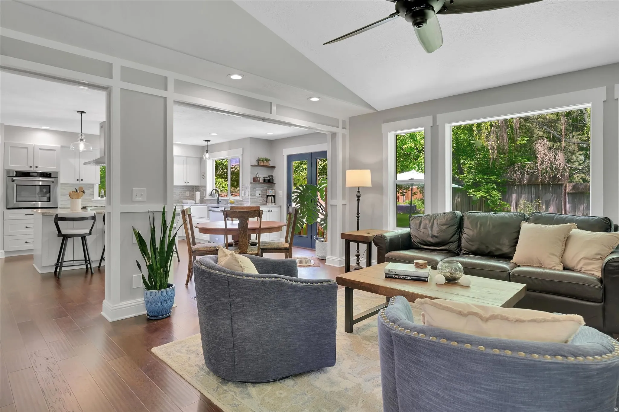 Open-concept living space featuring wood-finish flooring, a vaulted ceiling, and multiple windows