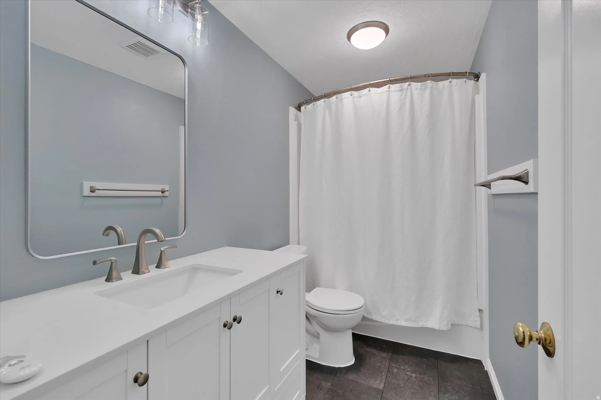 Bathroom featuring a white vanity with brushed nickel hardware, an undermount sink, and a rectangular mirror