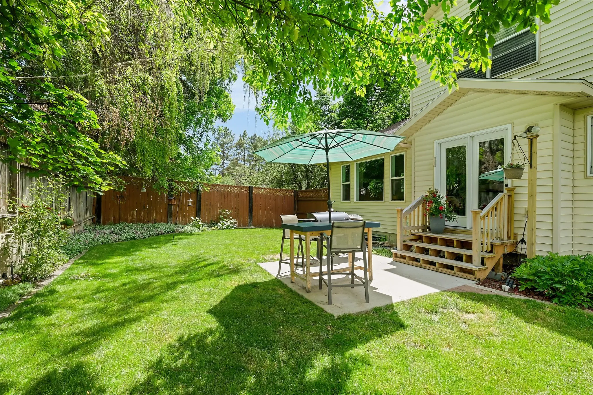 Expansive green lawn with mature trees and a privacy fence