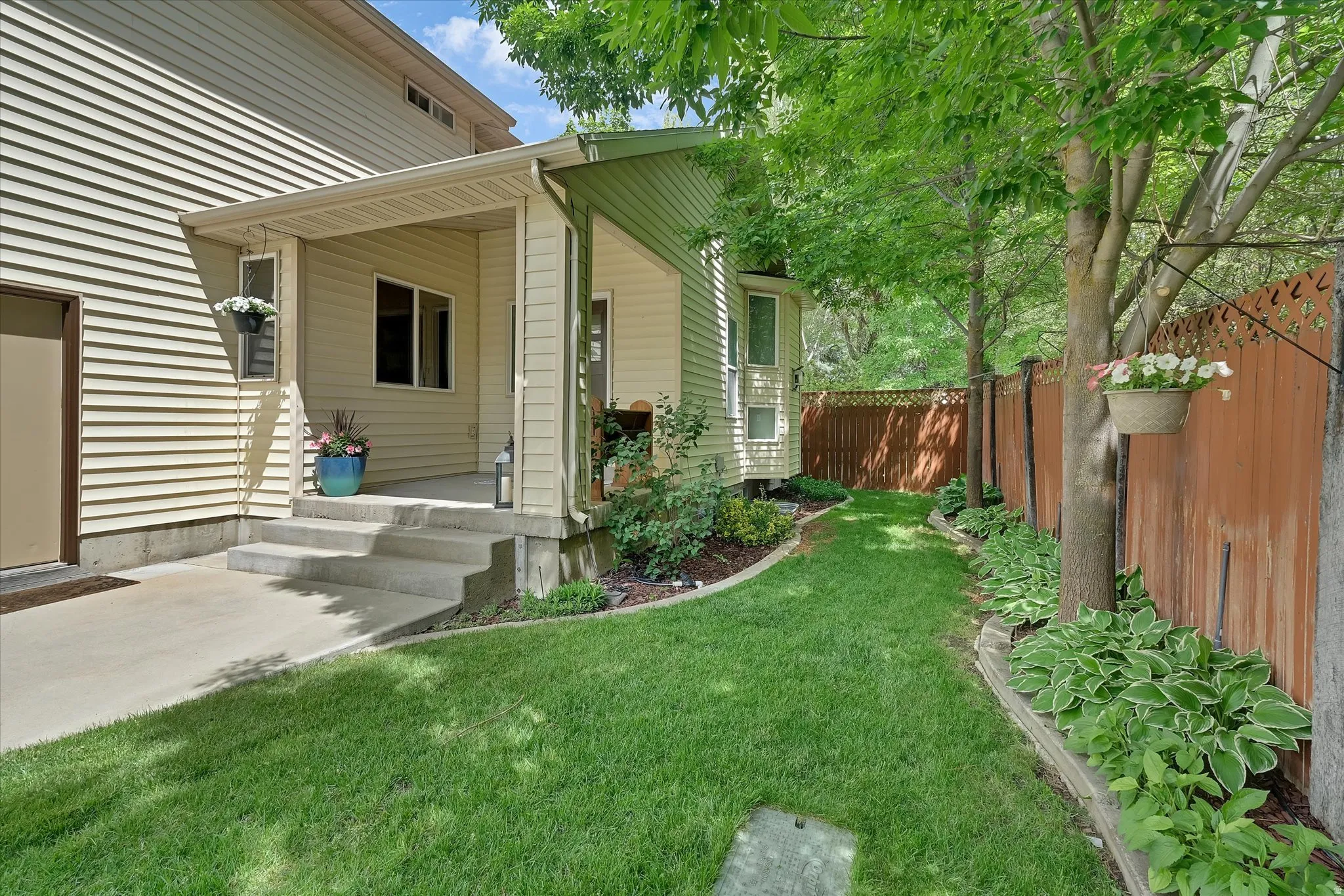 Expansive grassy yard area with mature trees and a wood privacy fence