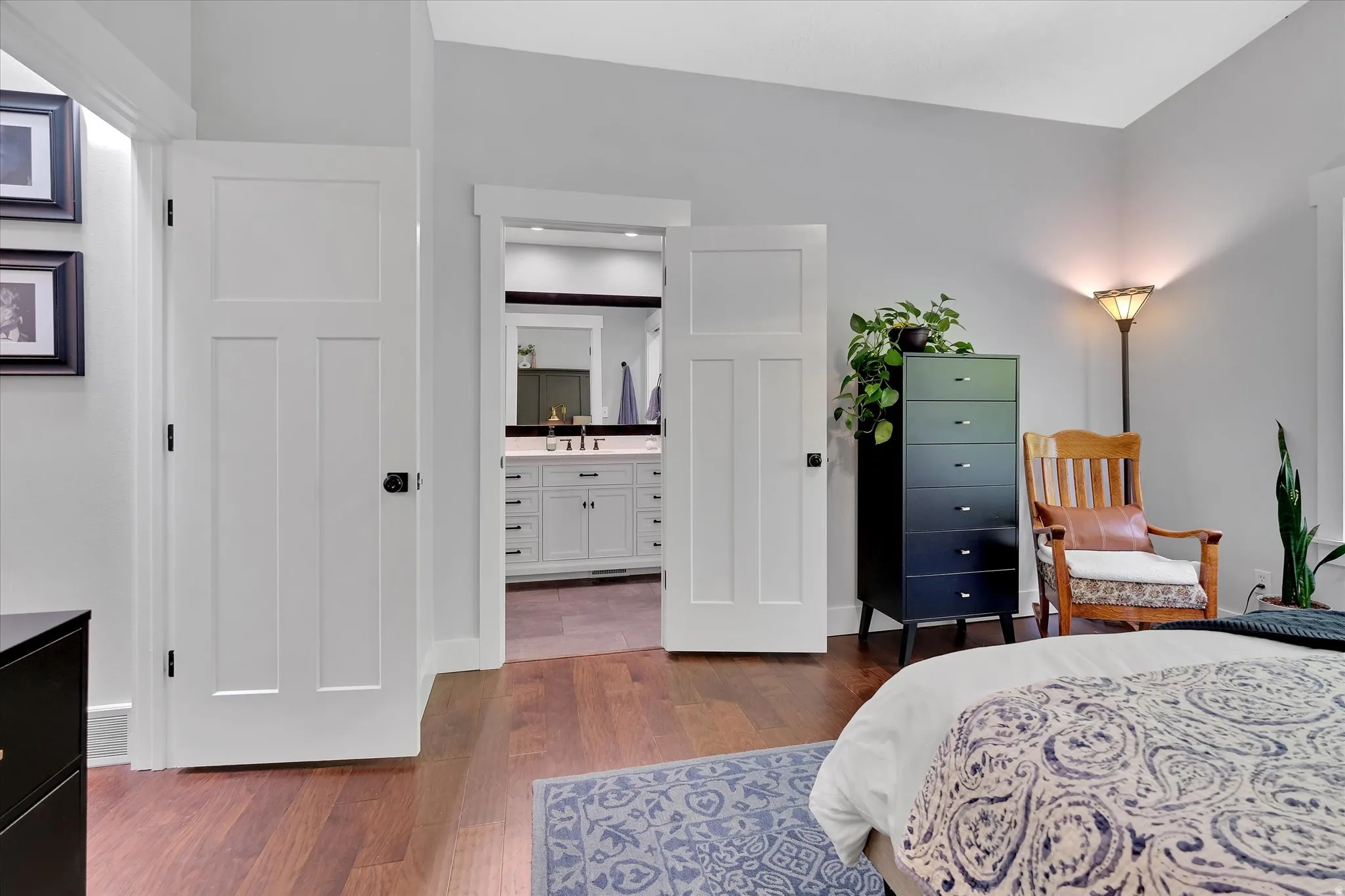 Spacious interior featuring rich wood-finish flooring, light gray walls, and white Craftsman-style doors with dark hardware