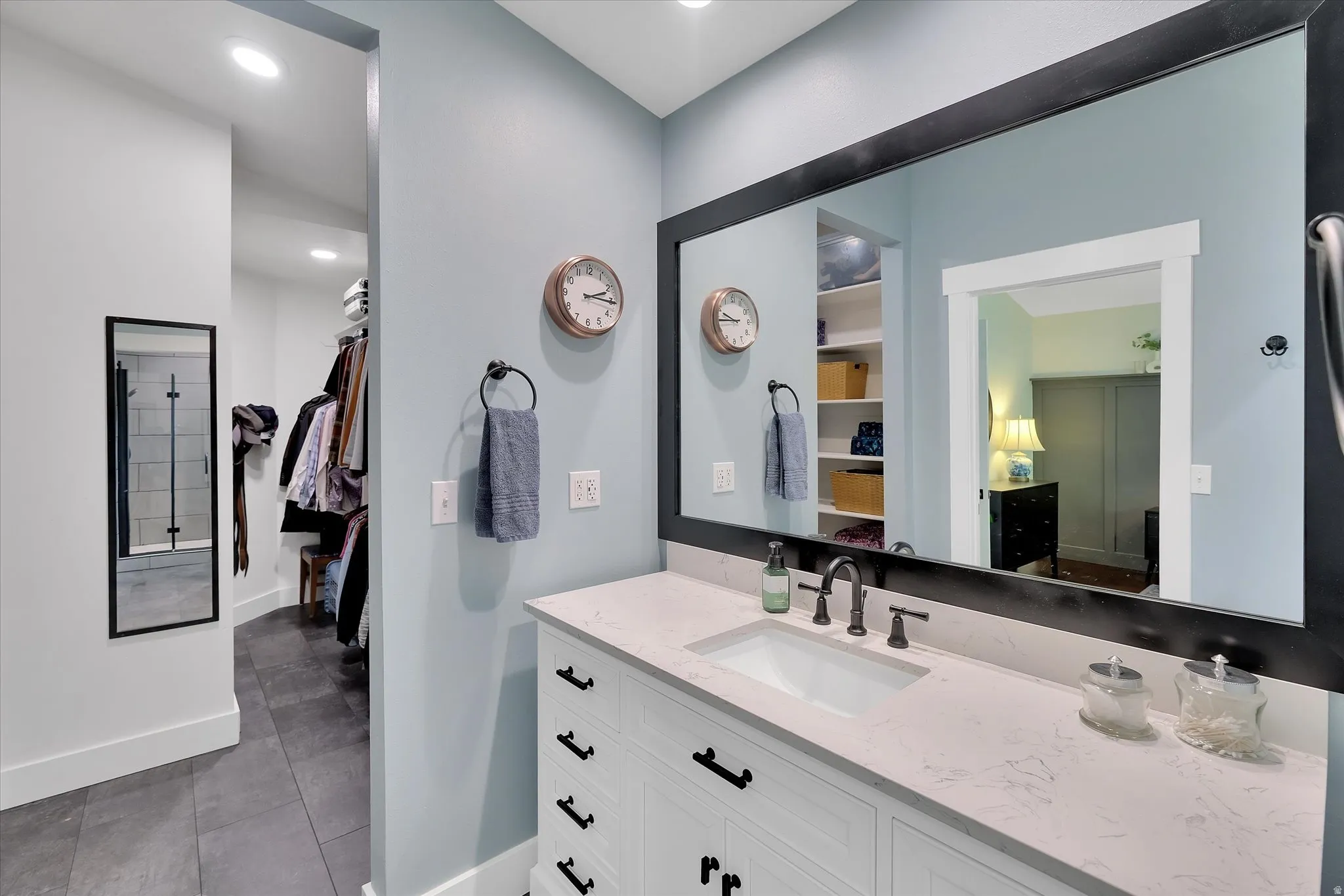 Bathroom vanity featuring a rectangular undermount sink, a light-toned countertop, and white cabinetry with dark hardware