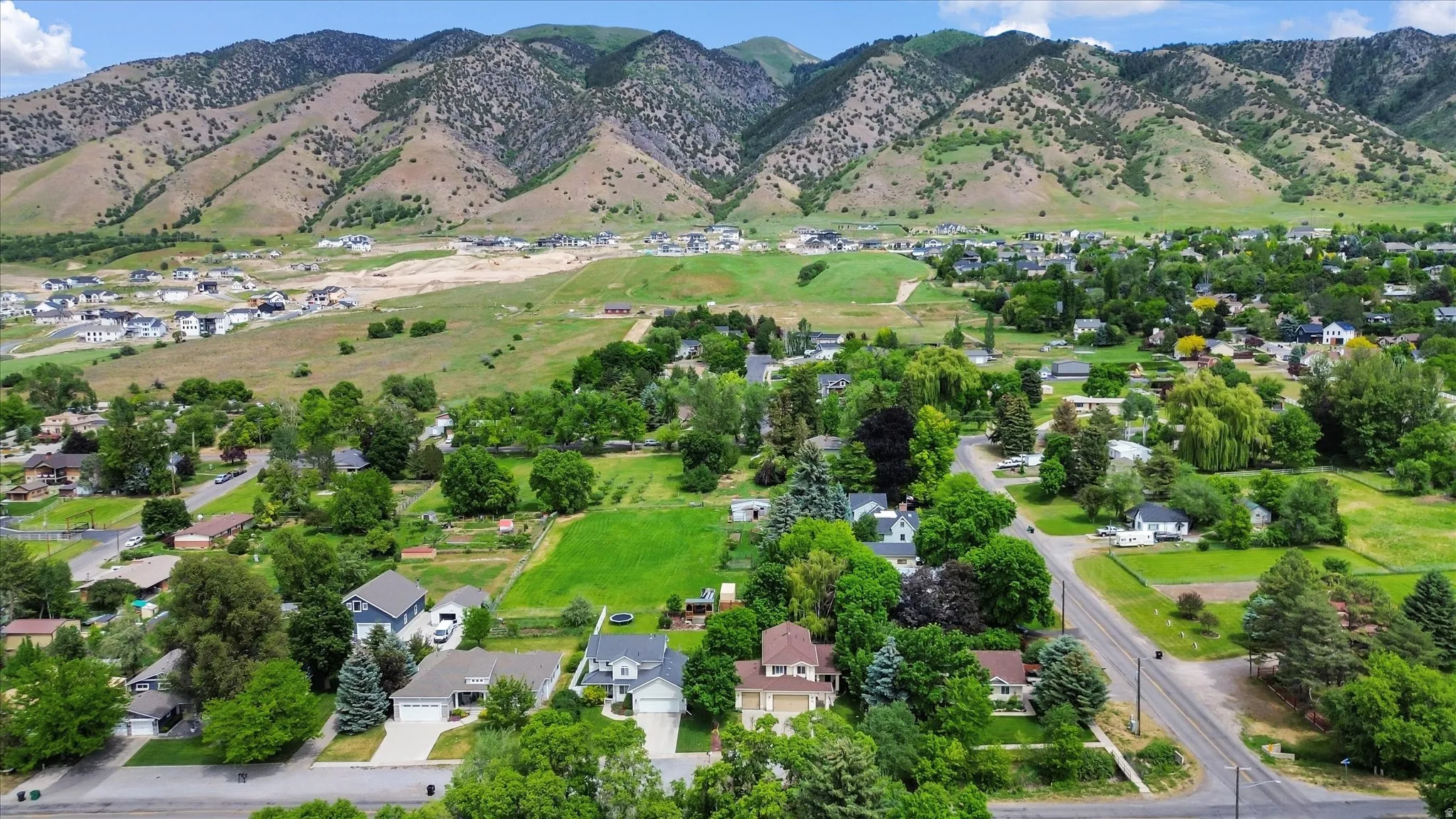 Expansive aerial landscape featuring a residential area nestled against a prominent mountain range