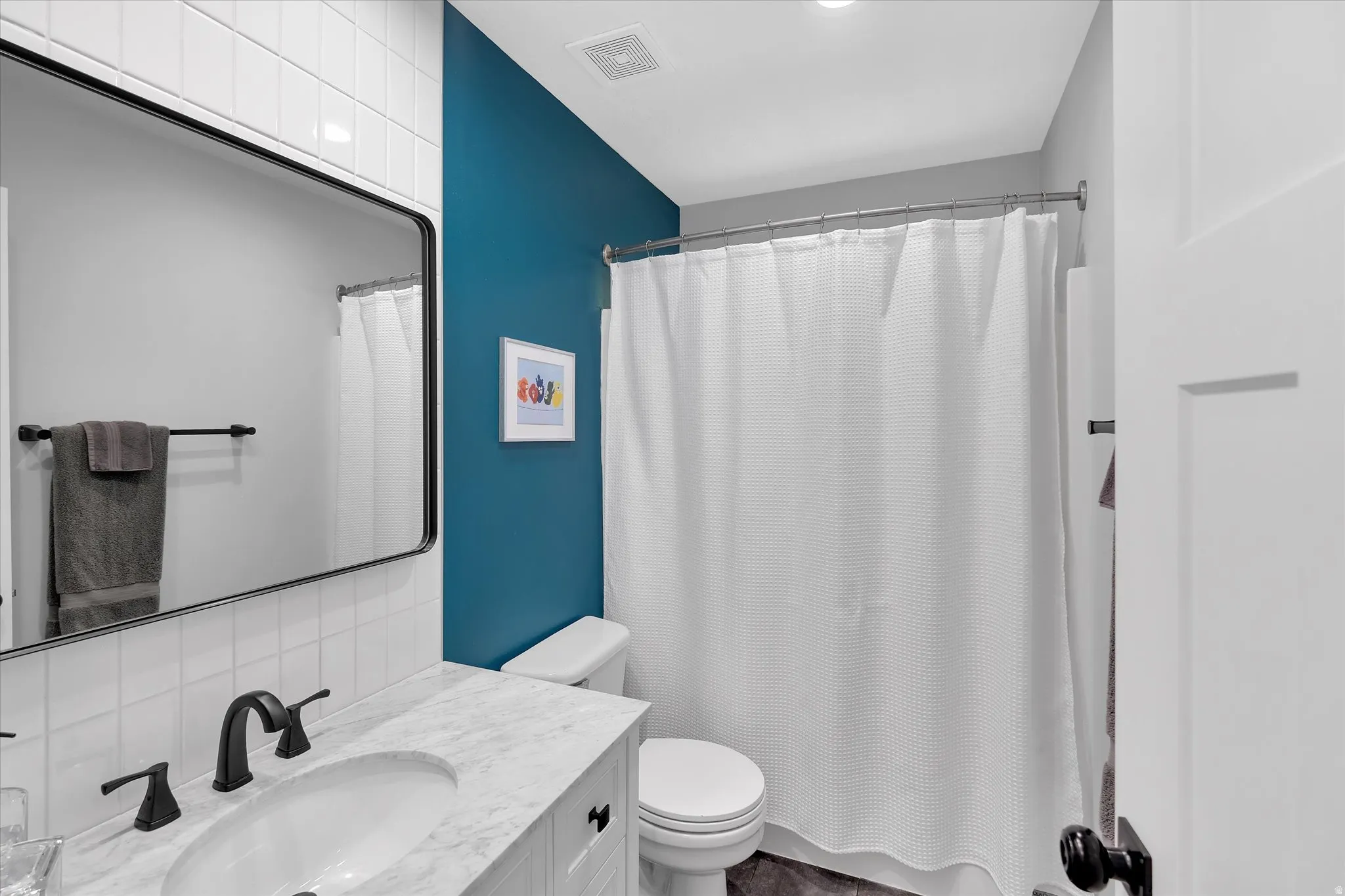 Bathroom featuring a vanity with a light-toned countertop, a rectangular undermount sink, and matte black fixtures