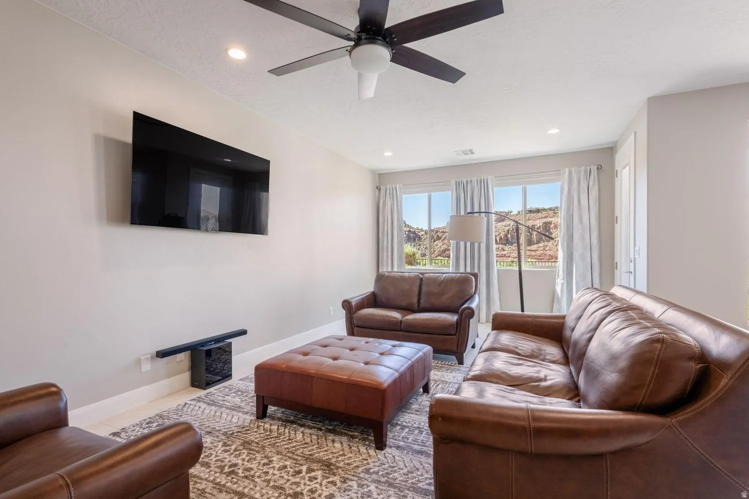 Living area with a wall-mounted television, recessed lighting, and a ceiling fan