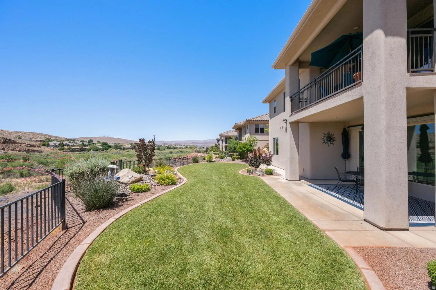 Expansive turf lawn bordered by decorative rock landscaping and a perimeter fence