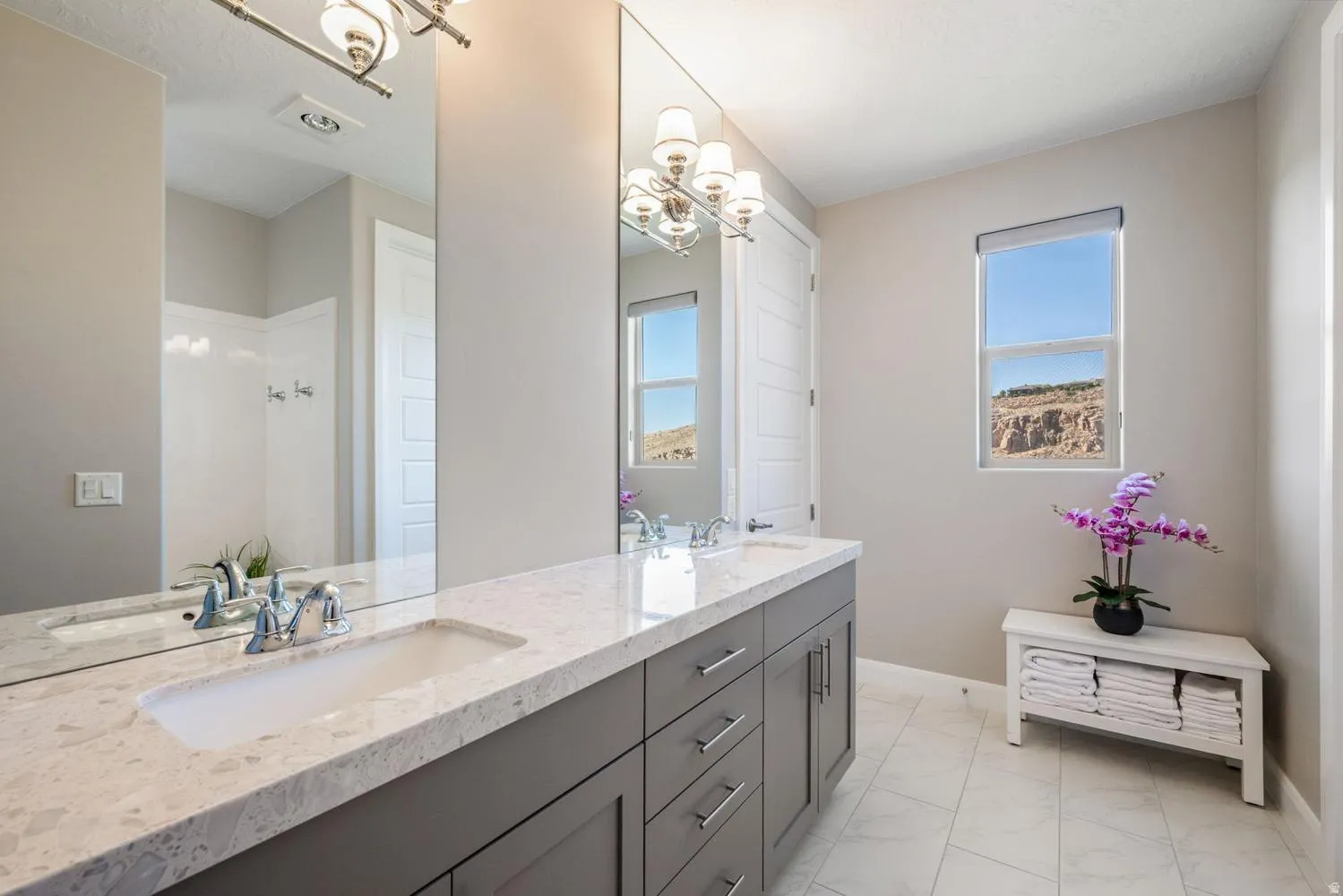 Spacious double vanity featuring an integrated sink, stone countertop, and gray cabinetry with chrome hardware