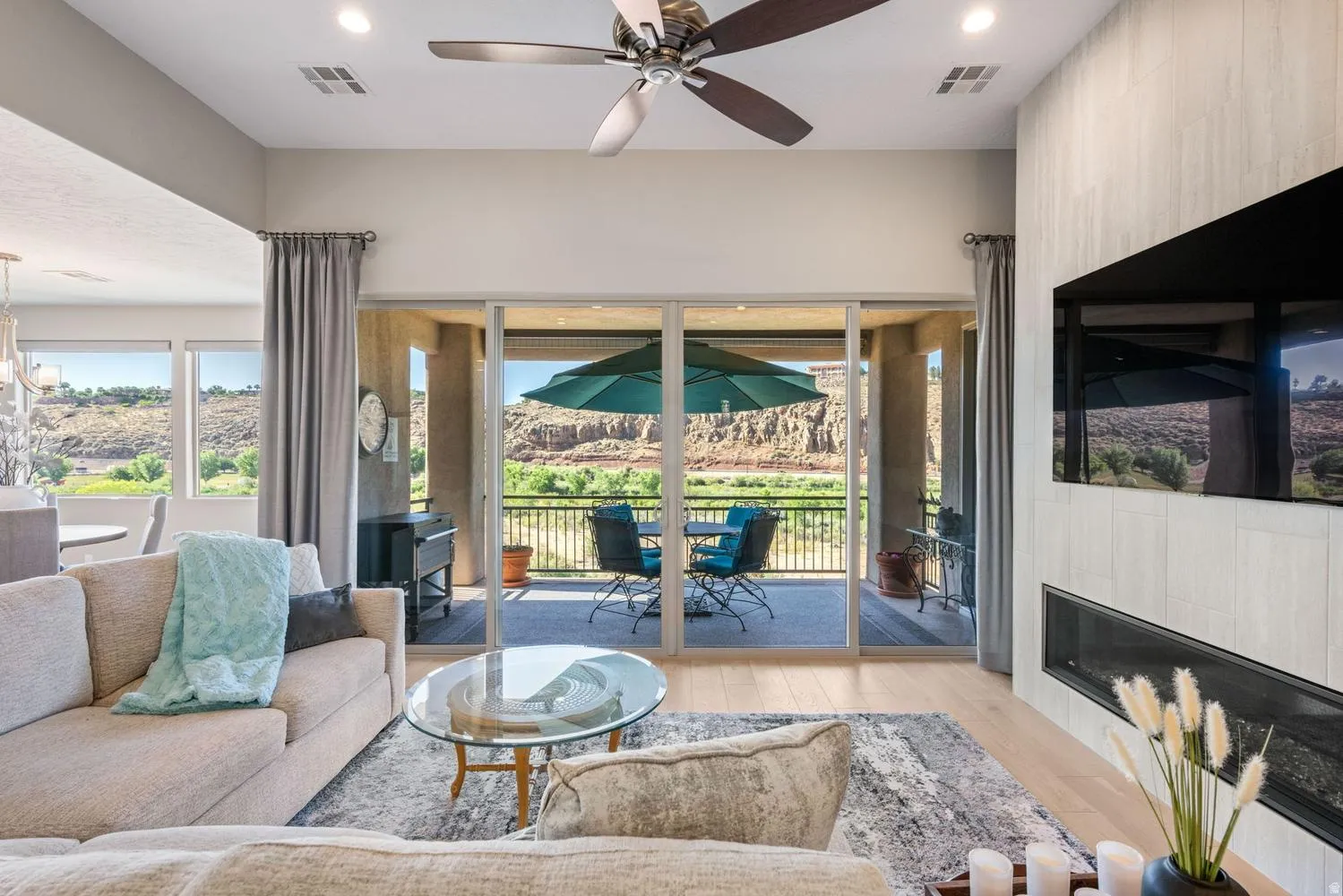 Open-concept living area featuring light wood-finish flooring and a built-in linear fireplace with a textured accent wall