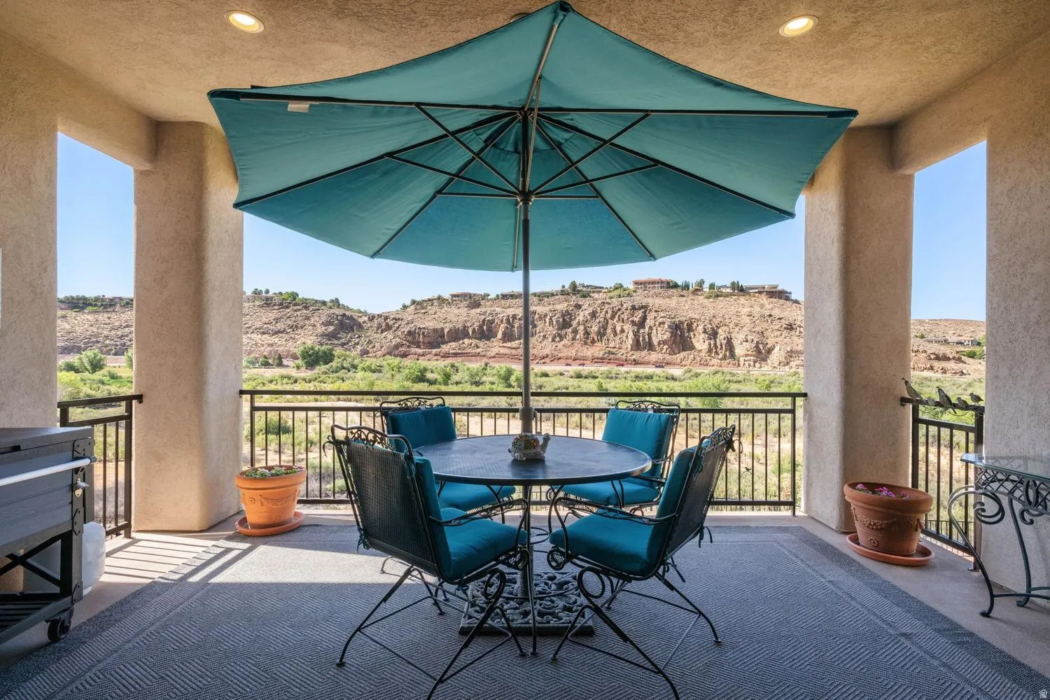 Covered outdoor living space featuring recessed lighting, a stone-finish floor, and black metal railings