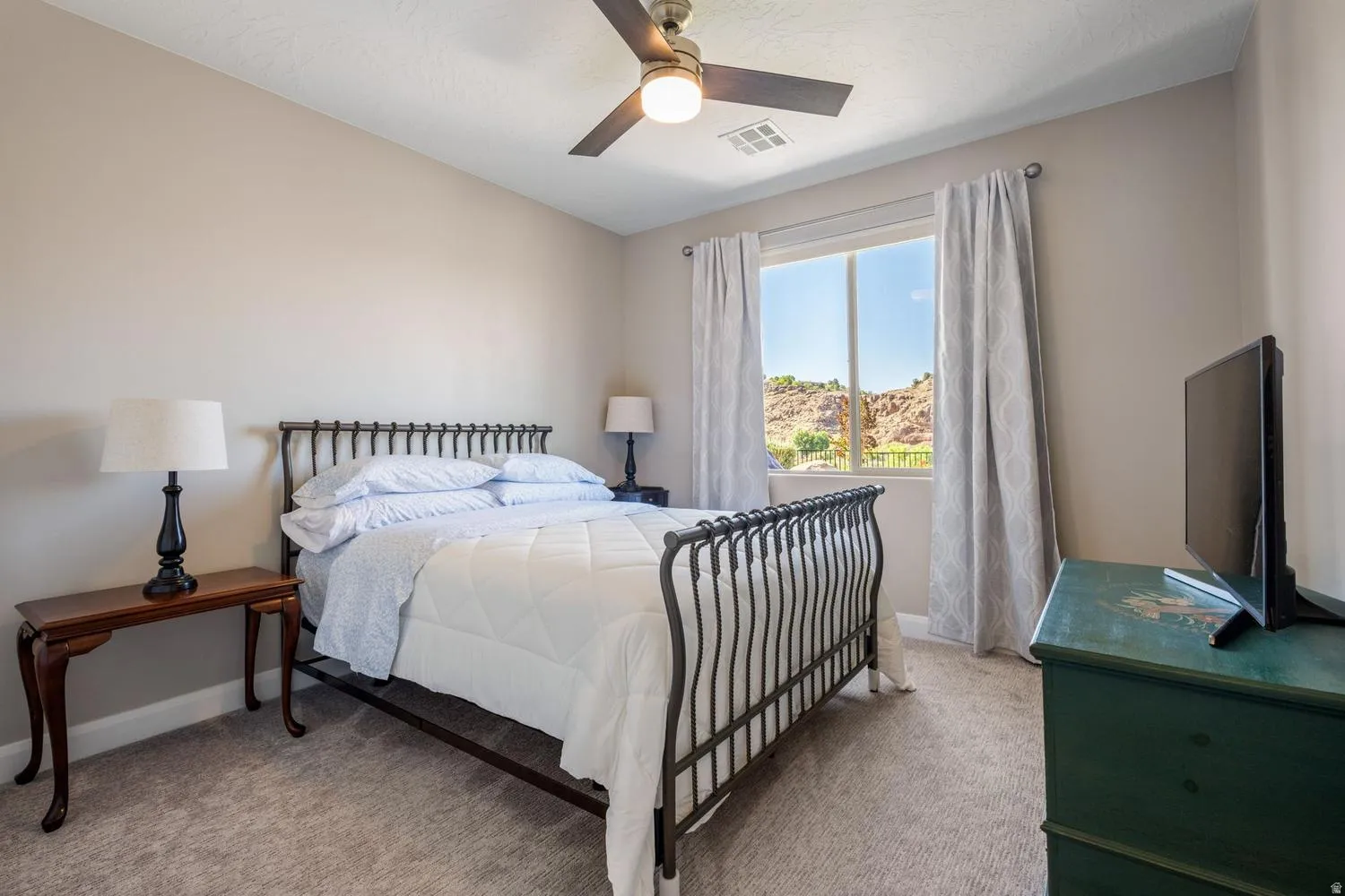 Bedroom featuring a window with exterior rock formations, ceiling fan, and carpeted flooring