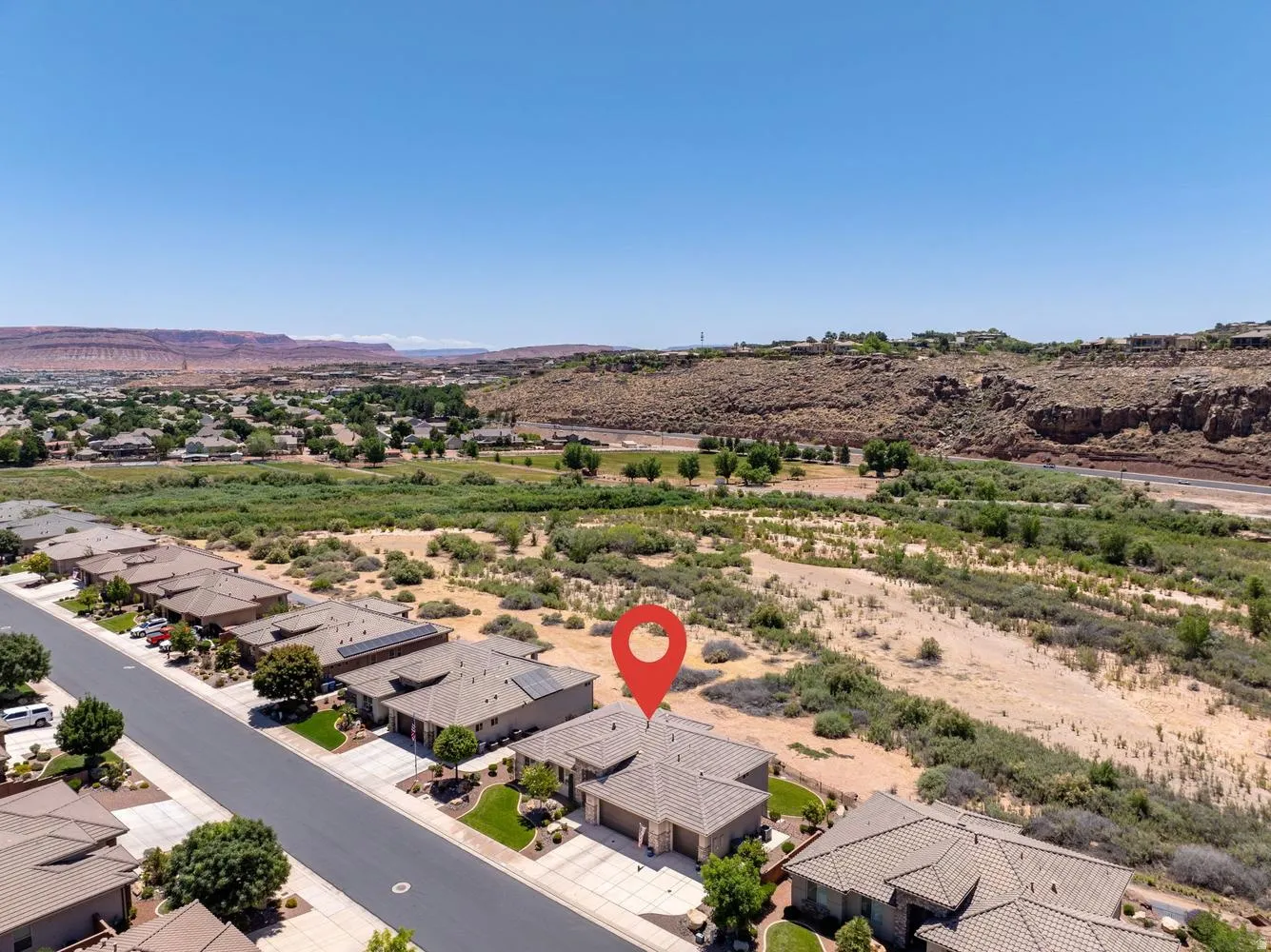 Aerial perspective showcasing the property's location within a residential neighborhood, featuring a paved street and surrounding natural desert landscape