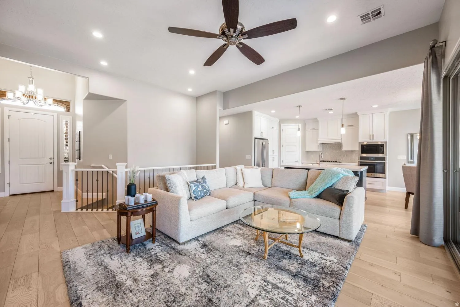 Open-concept living area featuring light wood-finish flooring, recessed lighting, and a ceiling fan