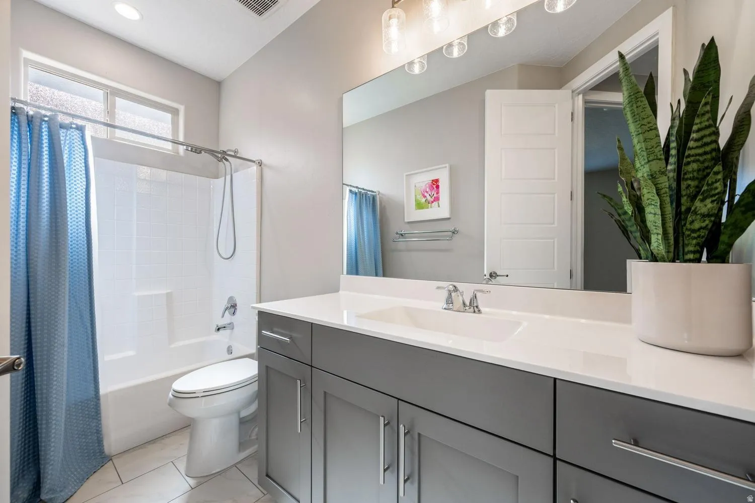Bathroom vanity featuring a light-colored countertop, an integrated sink, and gray cabinetry with brushed nickel hardware