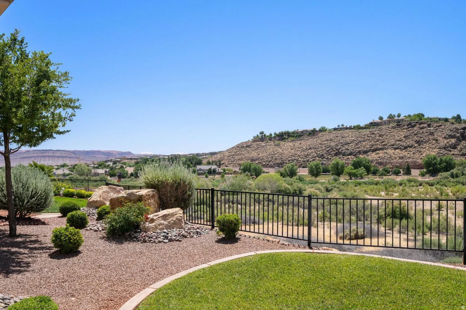 Expansive backyard space featuring a manicured lawn, decorative rock landscaping, and mature shrubbery