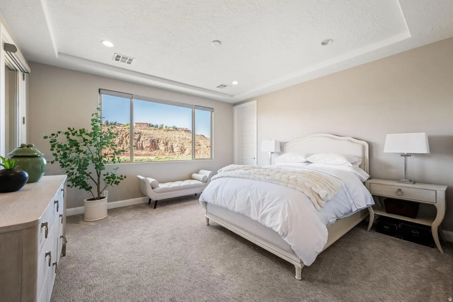 Recessed lighting illuminates a spacious room featuring a broad window with desert rock formations in the background