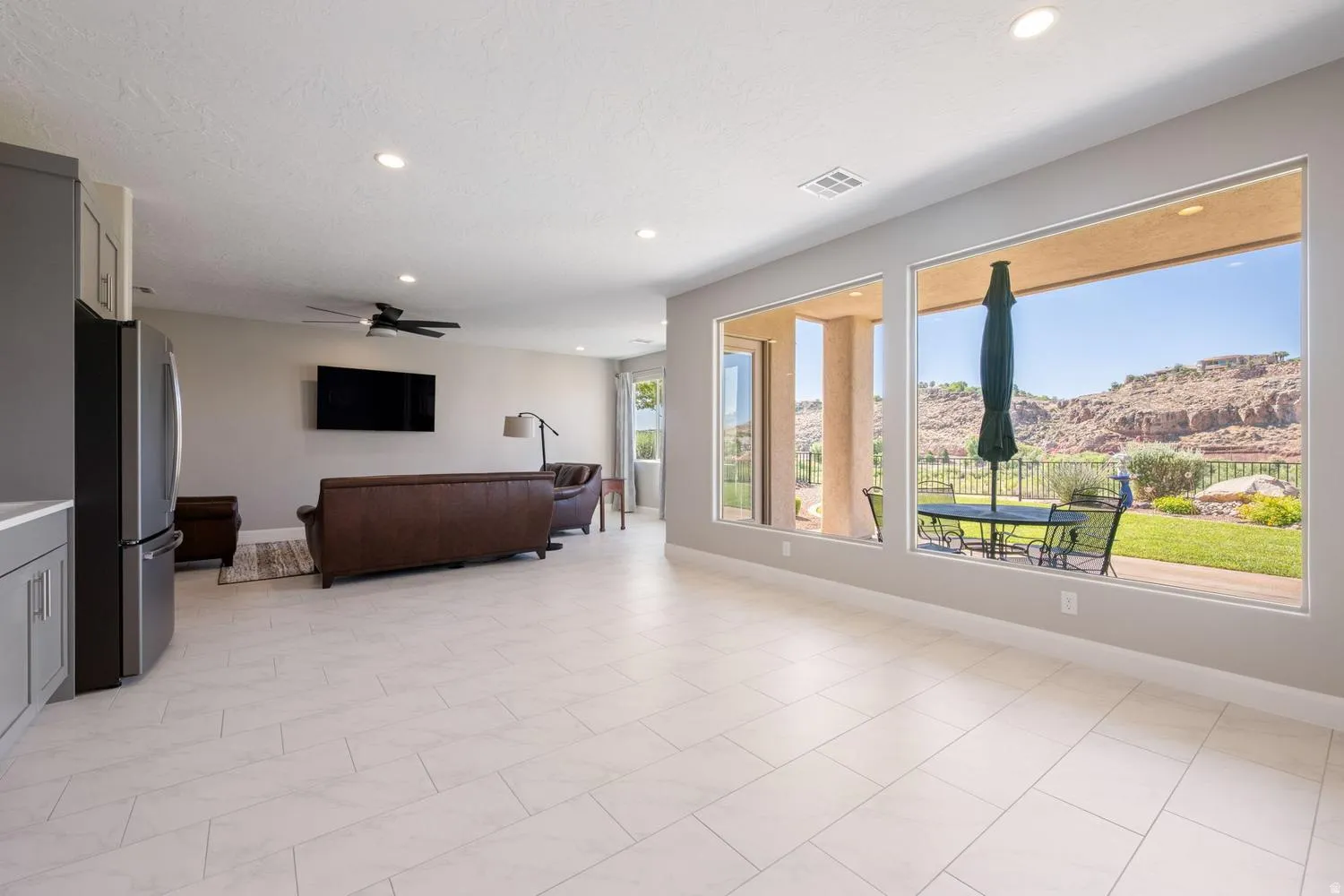 Spacious interior featuring large windows, light-toned tile flooring, recessed lighting, and a neutral color palette