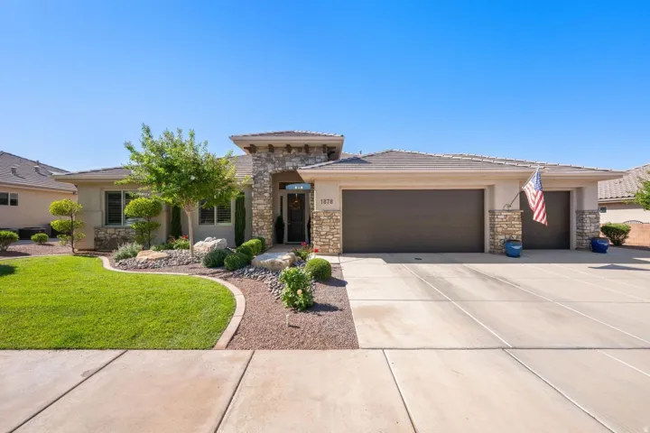 Contemporary stucco and stone exterior featuring a two-car garage, a separate single-car garage, and a concrete driveway