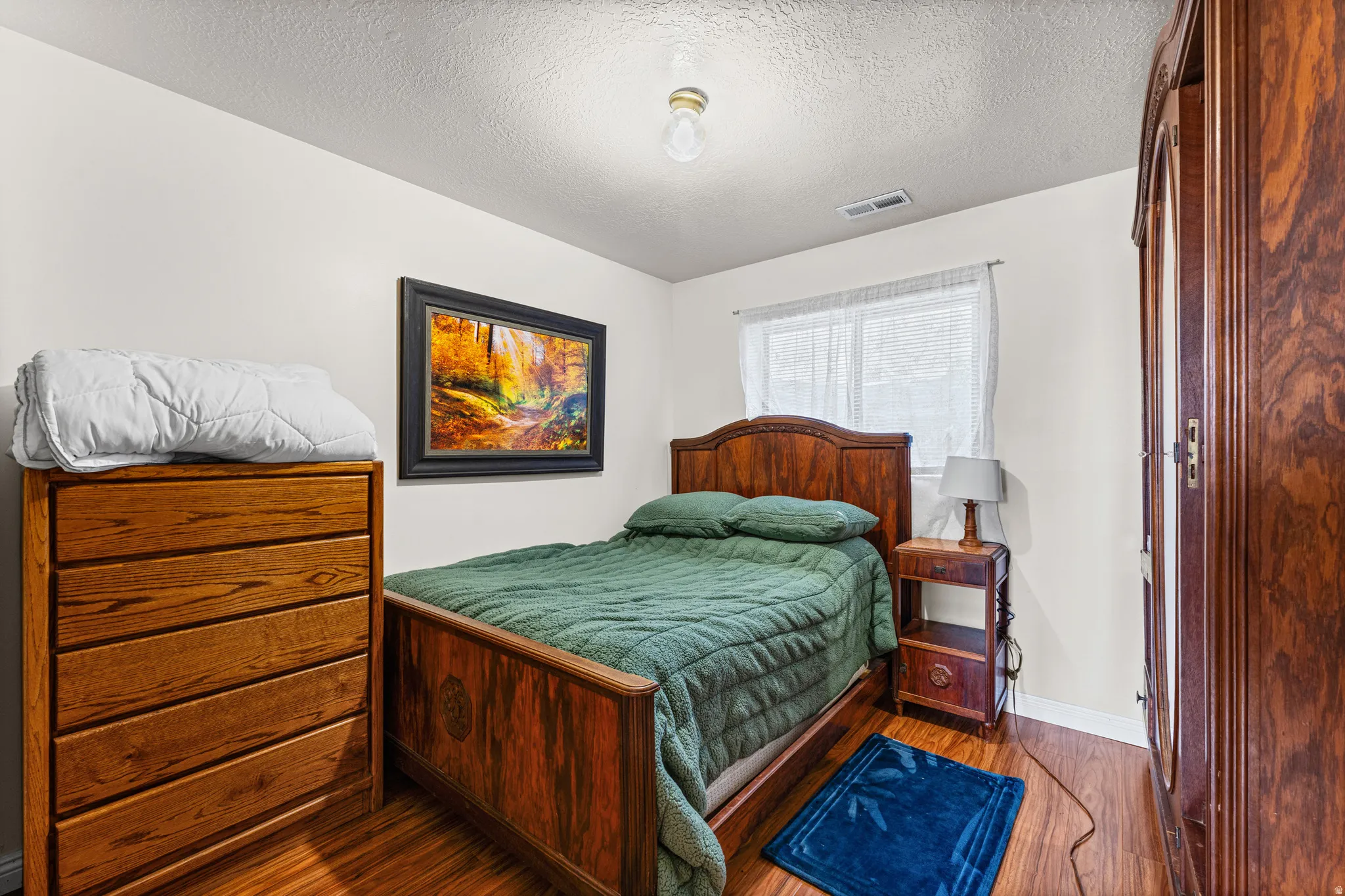 Room featuring wood-finish flooring, light-toned walls, and a window with white blinds