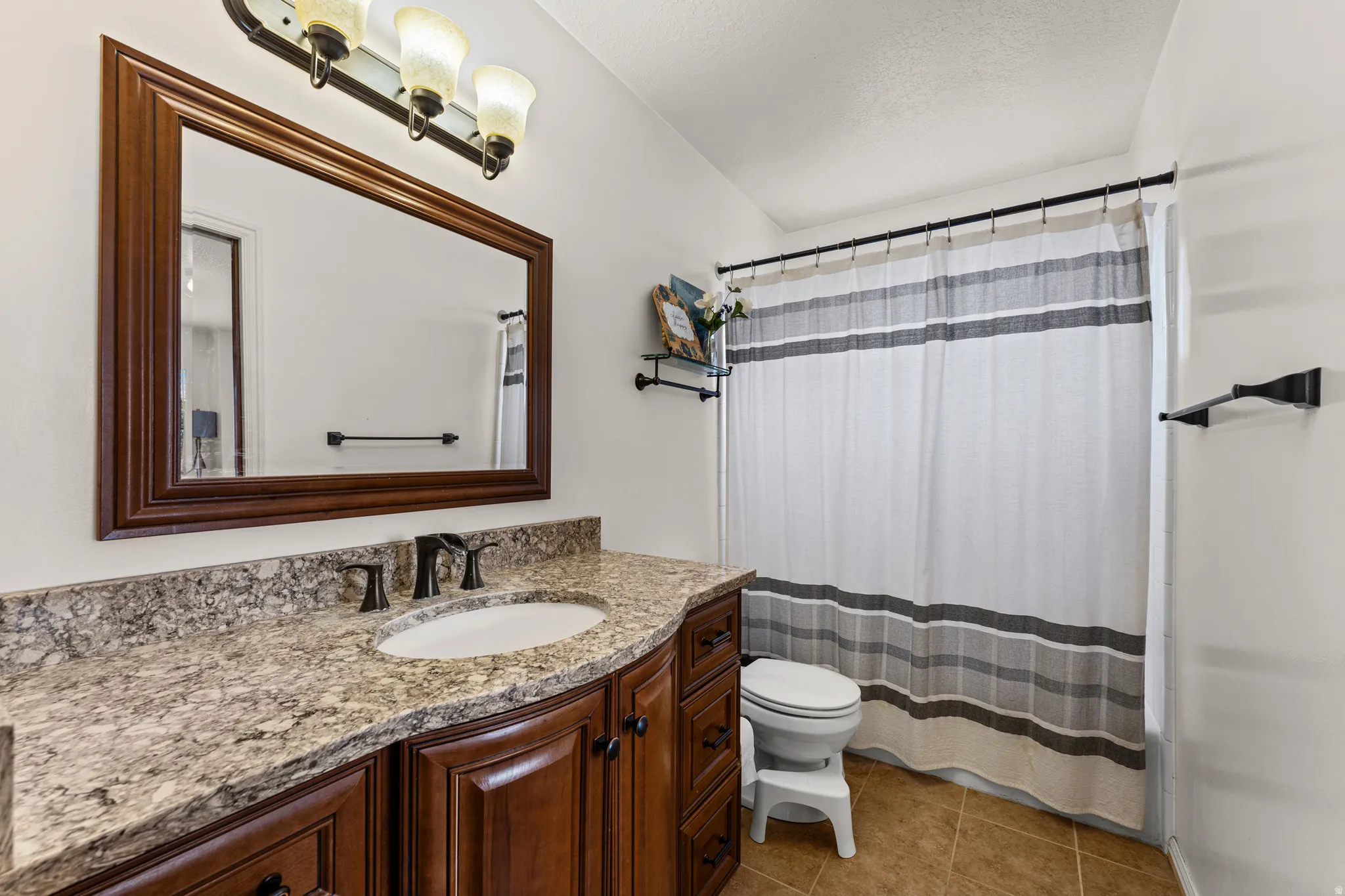 Bathroom featuring a wood-finish vanity with an integrated sink and stone countertop