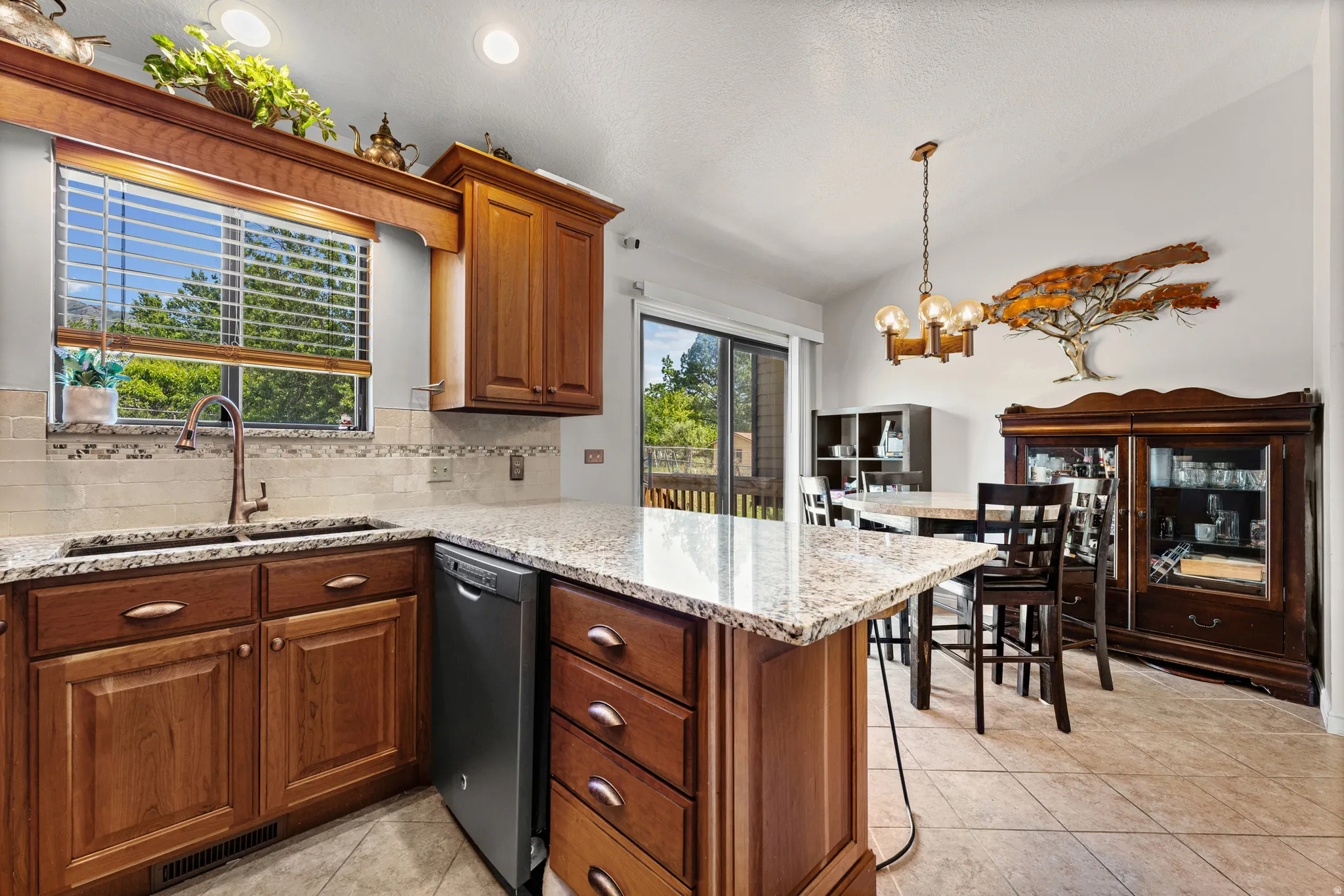 Kitchen featuring granite countertops, wood cabinetry, a tile backsplash, and a built-in dishwasher