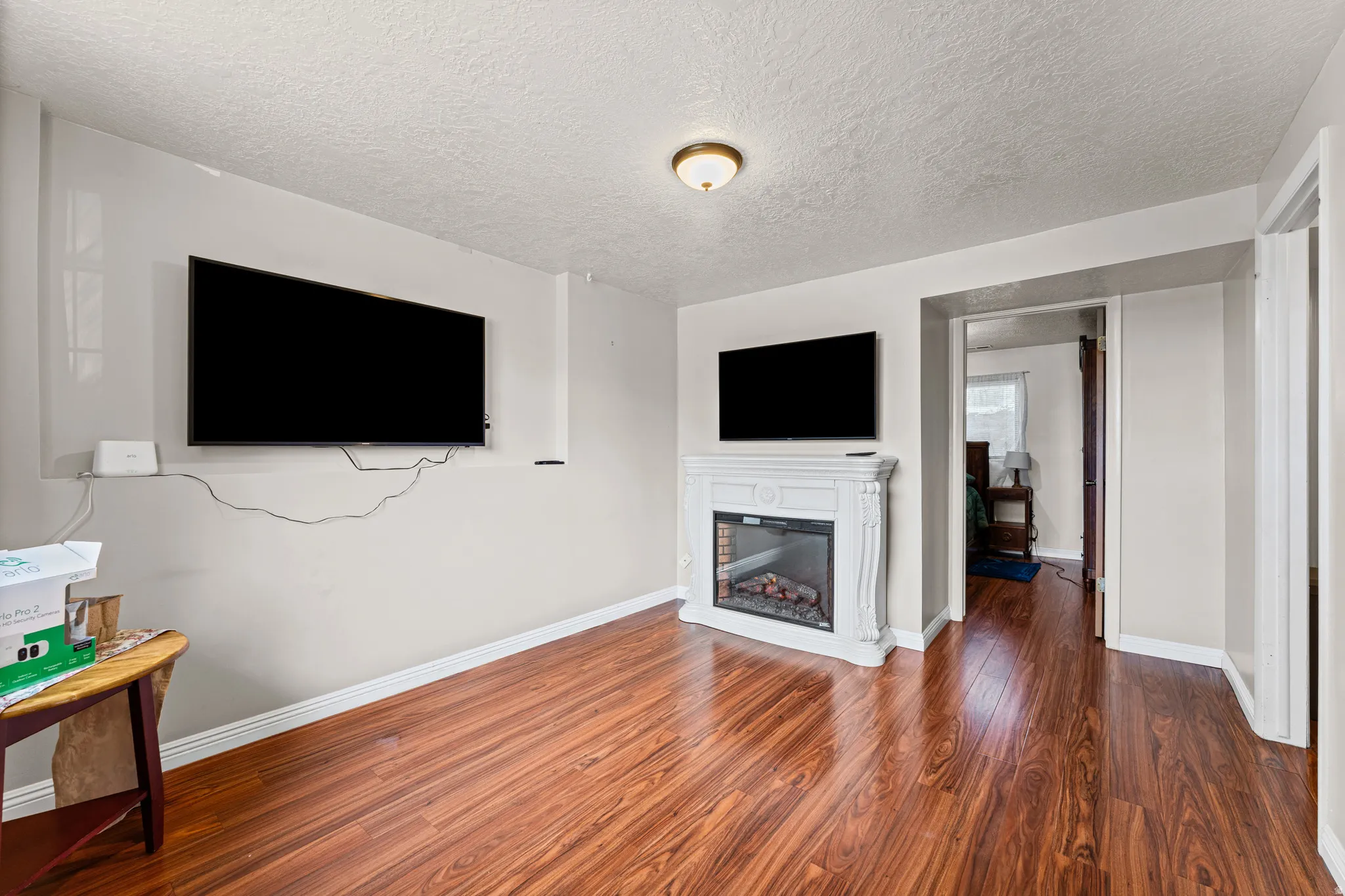 Spacious living area featuring wood-finish flooring and a decorative electric fireplace with a white mantel