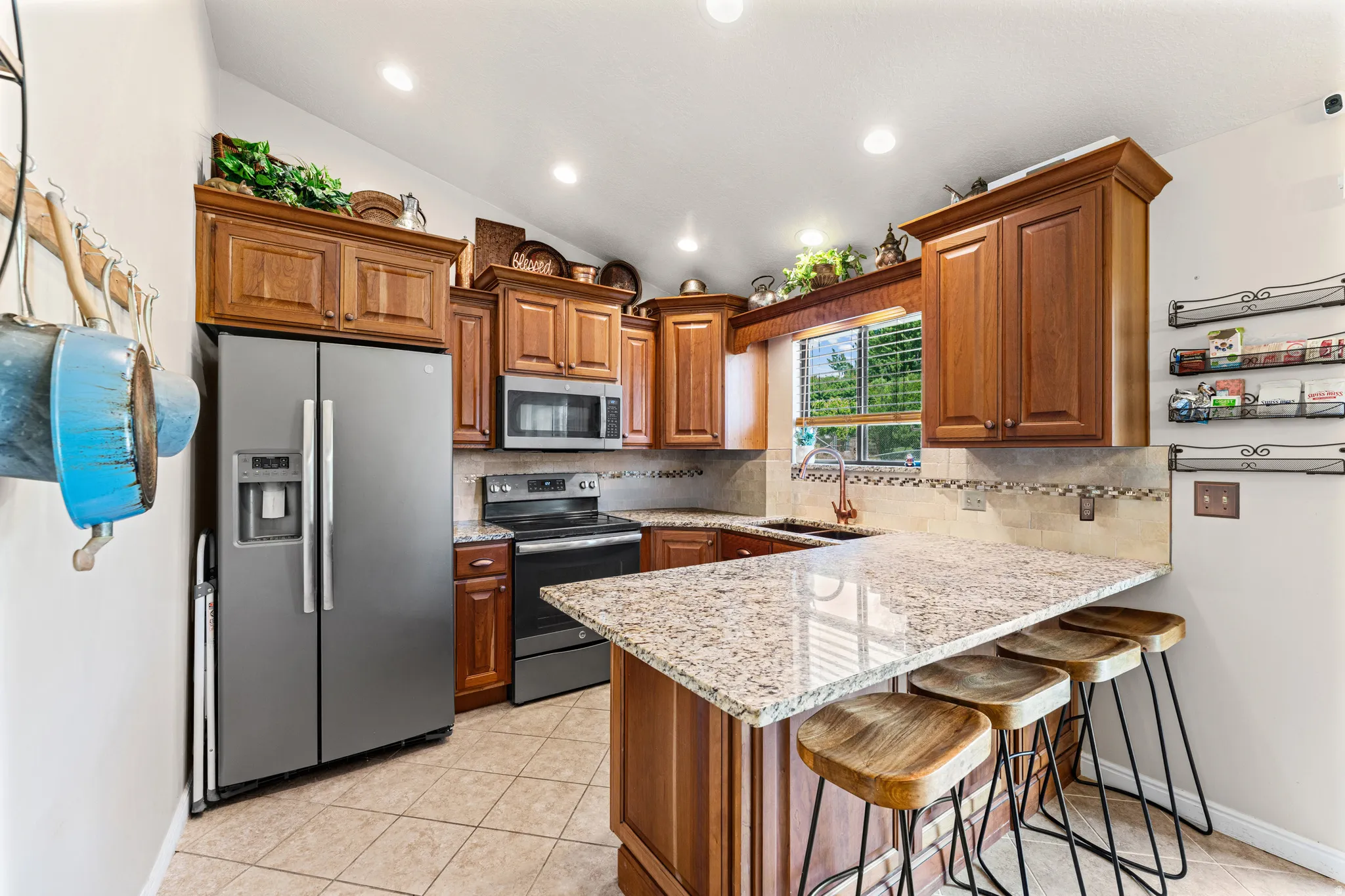 Kitchen featuring wood cabinetry, granite countertops, tile flooring, stainless steel appliances, and recessed lighting
